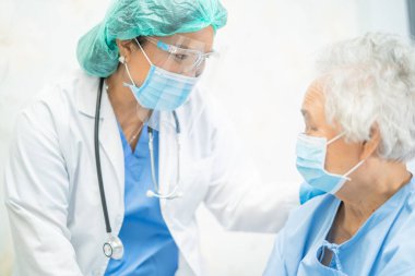 Yüz maskesi takan Asyalı bir doktor ve karantina hastanesi koğuşundaki Covid-19 Coronavirus salgınını kontrol etmek için PPE giysisi..