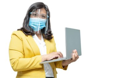 Asyalı iş kadınları beyaz arka planda maske ve yüz kalkanı takarak dizüstü bilgisayar kullanıyor. Ofiste Covid-19 Coronavirus salgınını korumak için yeni bir normal..