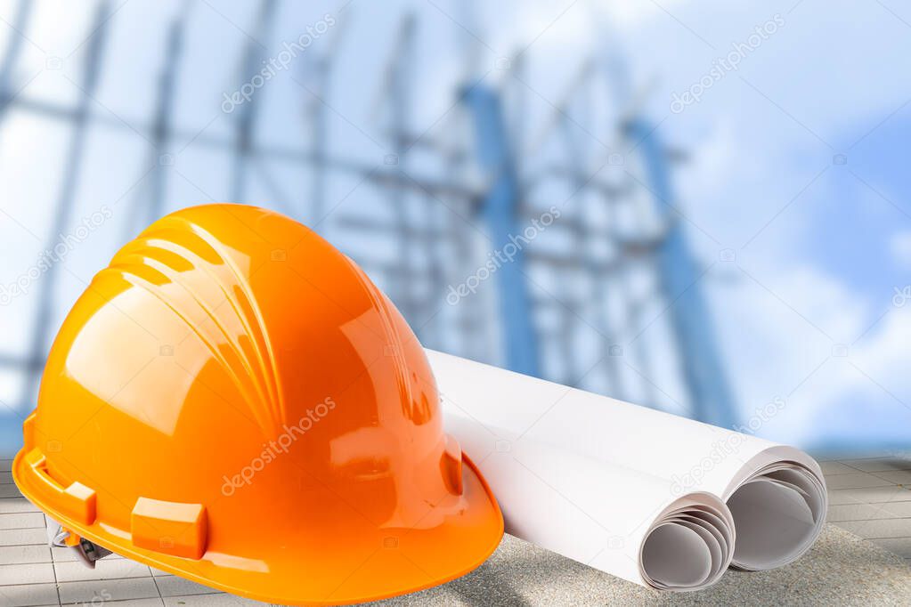 Orange construction helmet with blueprint, engineer safety concept.