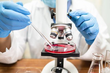 Laboratuvarda mikroskopla çalışan Asyalı biyokimyacı ya da mikrobiyolog. Coronavirus salgınını korumak için. Covid19, bakteri ve mikroplar..