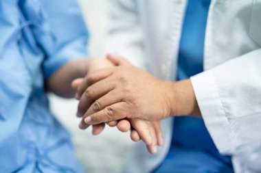 Asyalı yaşlı ya da yaşlı kadın hasta ile el ele tutuşmak. Sevgi, ilgi, cesaret ve empati, hemşire hastanesi koğuşunda sağlıklı ve güçlü tıbbi konsept.