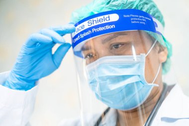 Yüz maskesi takan Asyalı bir doktor ve karantina hastanesi koğuşundaki Covid-19 Coronavirus salgınını kontrol etmek için PPE giysisi..