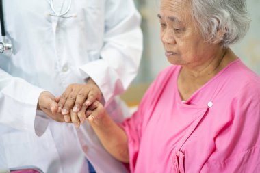 Asyalı yaşlı ya da yaşlı kadın hasta ile el ele tutuşmak. Sevgi, ilgi, cesaret ve empati, hemşire hastanesi koğuşunda sağlıklı ve güçlü tıbbi konsept.