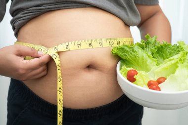 Koca göbekli, şişman, kilolu ve sağlıklı yiyecekleri olan Asyalı bir kadın..