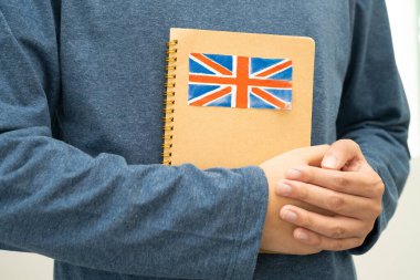 İngilizce öğren, Asyalı ergen öğrenci okulda bayraklı kitap tutuyor..