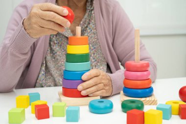 Bunama geçiren Asyalı yaşlı kadın hasta pratik motor beceri rehabilitasyonu öğreniyor.