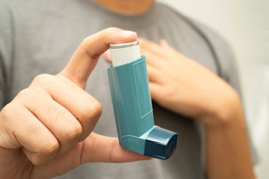Astım ve kronik obstrüktif akciğer hastalığı COPD, Asyalı genç adam ölçülü doz solunum cihazı kullanıyor..