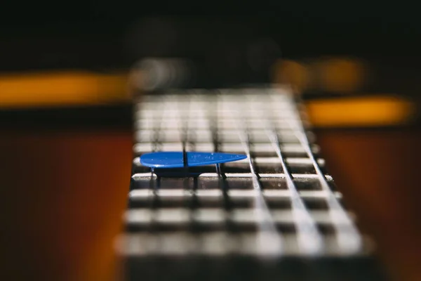 guitar worn frets and blue pick under the strings