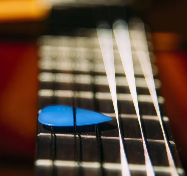 guitar worn frets and blue pick under the strings
