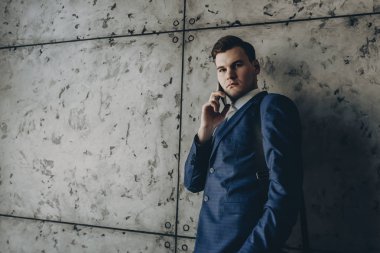 Gri bir duvara telefonda konuşan genç emin icra.