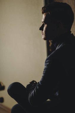 Bir sandalyede oturuyor ve uzak düşünceli arıyorum işten sonra dinlenme kendine güvenen bir genç yönetici yan görünüm.