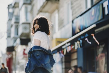Kot ceket giymiş ve kenti yakınlarındaki bir restoran fotoğrafçı için poz neşeli beyaz kadın.