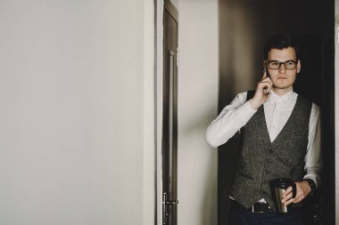 Bir fincan kahve el Office ile telefonda konuşan genç adam.