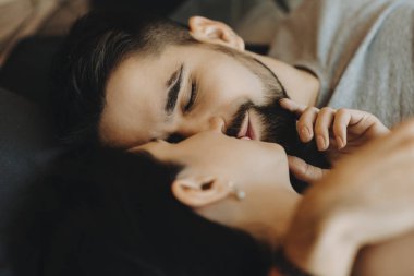 Sakallı güzel adam karısını yatakta döşeme öpüşme.