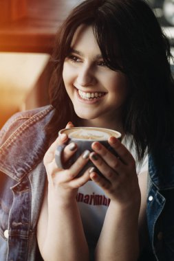 Güzel genç kız bir kafede kahve içme bir kot ceket giymiş.