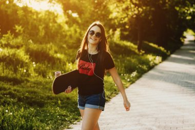 Elinde tutan bir paten ve mutlu bir şekilde uyanma parkta genç Kafkas kadın.