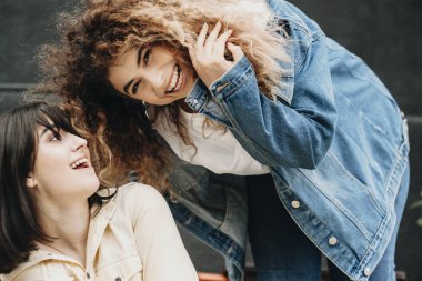 Genç kadın nerede kıvırcık kız esmer kız kız arkadaşı arıyor iken kamera gülüyor içine bakıyor şehirde eğlenmek şaşırtıcı.