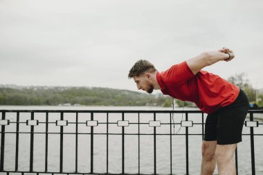 Ciddi bir genç atlet parkında çalıştırdıktan sonra germe yan görünüm.