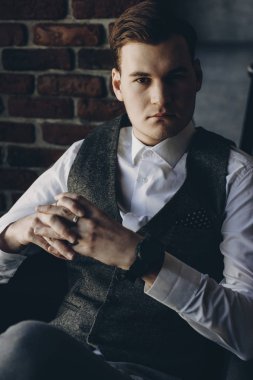 Bir sandalyede oturuyor ve ciddi görünümlü kameraya kendine güvenen genç işadamı.