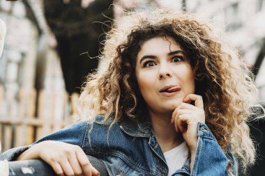 Fotoğrafçılara poz ve dilini gösterilen süre komik surat yapıyor bir sevimli vücut olumlu kıvırcık kız portresi kapatın.