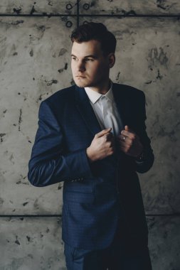 Yakışıklı bir genç Yöneticisi uzak seyir ve onun takım elbise eller ile tutarak portresi.