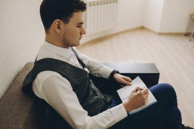 Bir kanepe sittin ve yaptığı iş hakkında her gün günlüğü yazma yakışıklı genç serbest meslek.