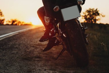 Bisikletiyle yolun yakınında gündoğumu bakarak otururken bir motosikletçi alt kısmı kırpılmış fotoğraf kapatmak .