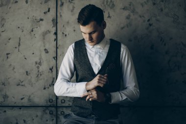 Yakışıklı işadamı gri arka planı olan bir ofiste giyinme.