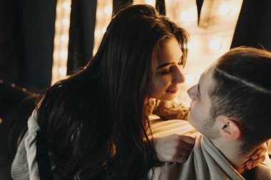 Güzel bir çift kucaklayan ve birbirlerine sıcak aydınlatma dekorasyon gülümseyen seyir yerde oturma portre kadar kapatın.