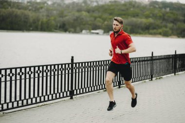 Sabah parkta ve müzik dinleme sırasında çalışan genç beyaz adam.