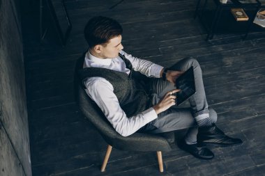 Bir sandalyede kalıyor ve dijital tablet gri bir ofiste çalışan bir işadamı Üstten Görünüm.