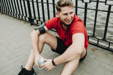 Katta oturan ve dinlenme ve göl çevresinde çalışan sabah sonra gülümseyen bir genç sağlıklı bir insan portresi.