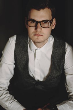 Yakışıklı genç yönetici bir sandalyede oturuyor ve kameraya izlerken gözlüklü portresi.