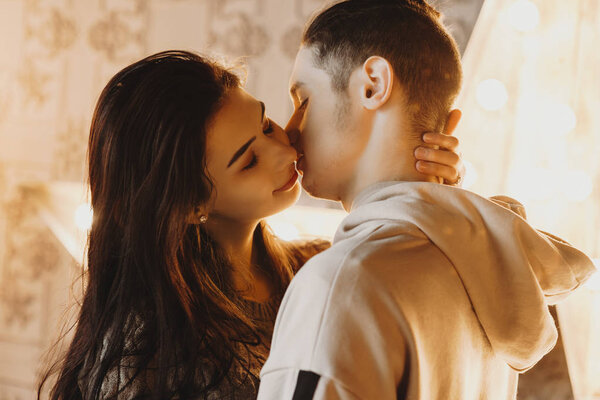 Close up portrait of a lovely young couple embracing while girl is trying to kiss her boyfriend.