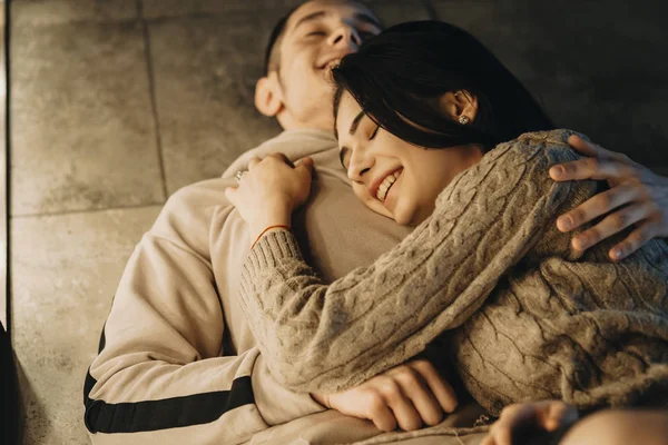 女の子は暖かい光に近い目を閉じて彼の彼氏の胸に傾いている間床笑いに傾いて素晴らしいカップルの肖像画 — ストック写真