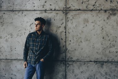 Gri bir duvar güzel denim beyaz esmer yaslanmış ve uzak gülümseyen arıyorsunuz.