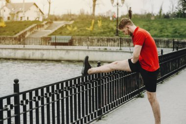 Genç Beyaz atlet parkında çalıştırmadan önce egzersizleri yapıyor.