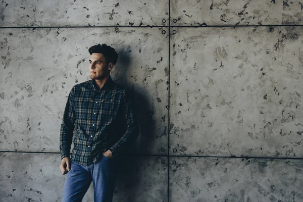 Gri bir duvar güzel denim beyaz esmer yaslanmış ve uzak gülümseyen arıyorsunuz.