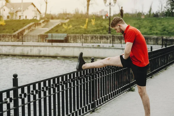 Genç Beyaz atlet parkında çalıştırmadan önce egzersizleri yapıyor.