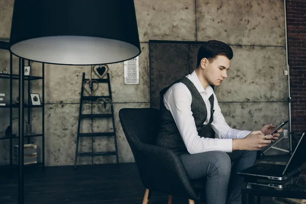 Young business man in his office, trading on smartphone.