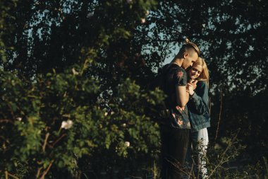 Gülümseyen aşağı bakıyor güzel genç beyaz çift doğada nerede evlat kucaklayan bir çiçek sevgisi için veriyor.