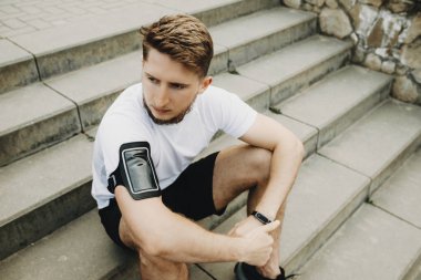 Parkta merdivenlerde oturan ve sabah egzersiz sonra dinlenme genç bir beyaz adam portresi.