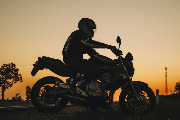 Вид Сбоку Человека Шлеме Который Едет Темной Дороге Мотоцикле Закате — стоковое фото