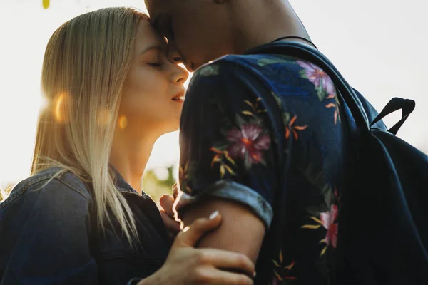 年轻有吸引力的男人和女人在夏天的衣服拥抱和触摸的鼻子和额头上背光背景下的作物视图 — 图库照片