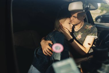 İnce güzel kucaklayan yaz giysileri yakışıklı genç sarışın bir kadın ona araba kapalı gözler ile ön koltuğunda oturan eğilerek kot ceket ile kaplı rahat