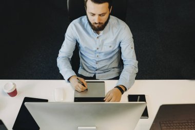 Yakışıklı adam ofiste masada oturan ve modern grafik tablet üzerinde çizim sakallı