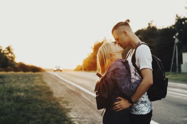 Genç adam ve yola yakın duran ve her diğer kırsal kesimde seyahat ederken öpüşme kadın yan görünüm