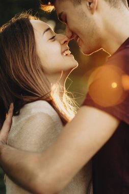Mutlu çift aşık kucaklayan ve arkada ayakta ışığını yaktı iken burun ile dokunmadan yan görünüm 
