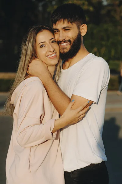 Sarışın Kadın Neşeyle Güneş Işığı Kameraya Bakarak Kucaklayan Sakallı Adam — Stok fotoğraf