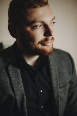 Sırıtıyor ve uzak duran gri arka plan üzerinde seyir kırmızı sakallı yakışıklı zarif adam